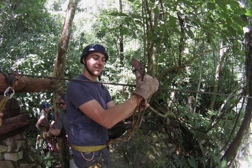 A person rappelling down a tree, surrounded by dense forest. 4