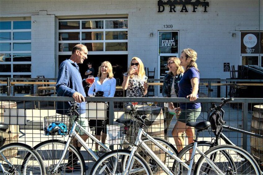 People standing near bicycles in front of a building with 'DRAFT' signage. 1