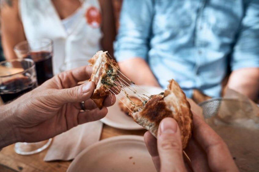 A person holding a piece of bread with cheese and greens. 4