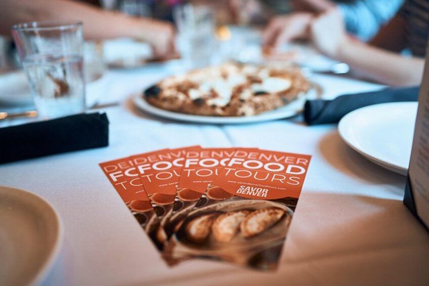 A brochure titled 'Deidenvender ECFOOD TOUR' on a table with a plate of food and glasses. 5