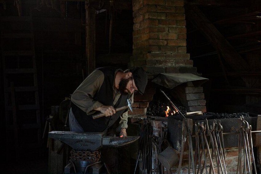 A blacksmith at work, hammering metal in a forge with a fire burning in the background. 3