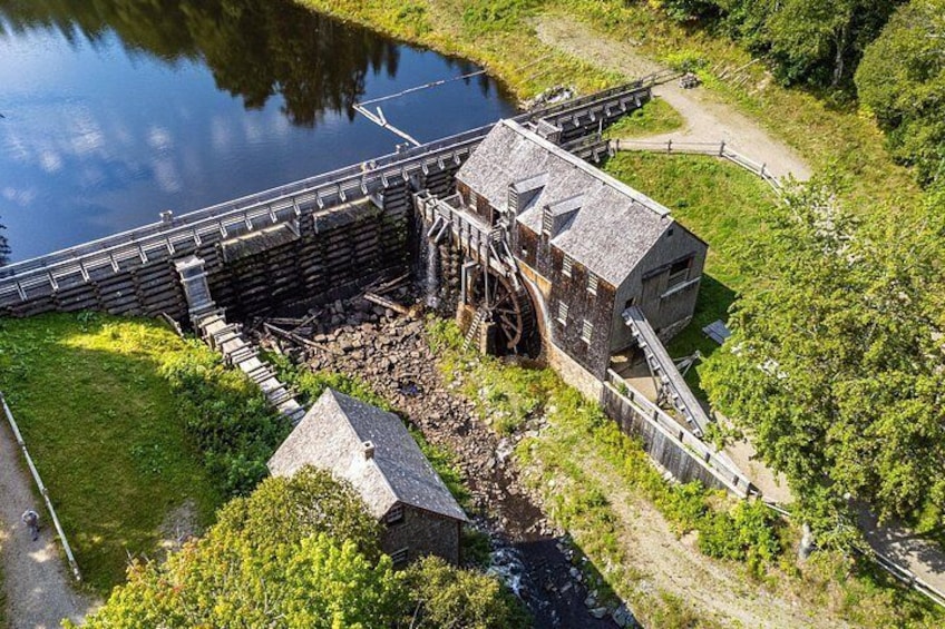 A watermill with a large wheel, a wooden structure, and a small building. 4