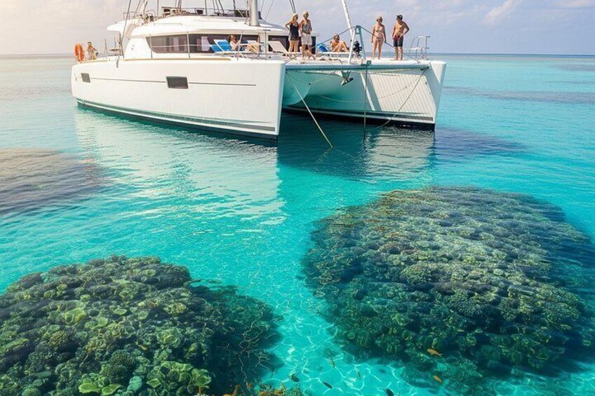 Un barco blanco con gente en la cubierta, agua turquesa cristalina y formaciones de coral. 3