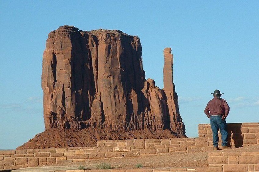 A man standing on a brick platform with a large rock formation in the background. 3