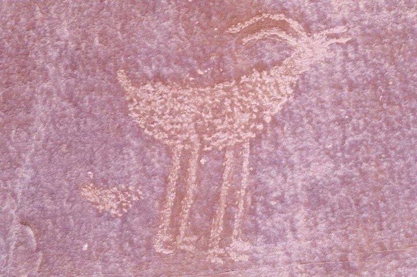 A faded petroglyph of a human figure with a bird, possibly a shaman or deity, on a rock surface. 2