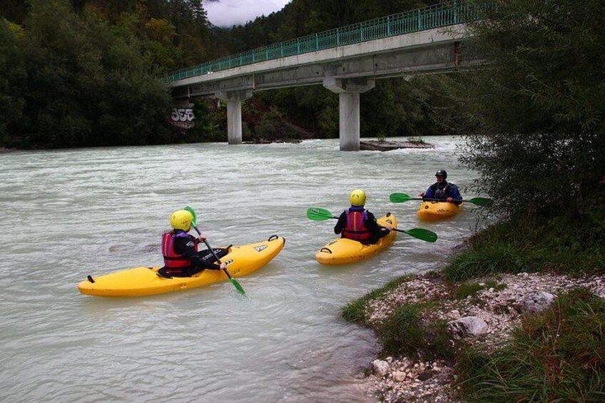 Three kayakers on a river with a bridge in the background. 2
