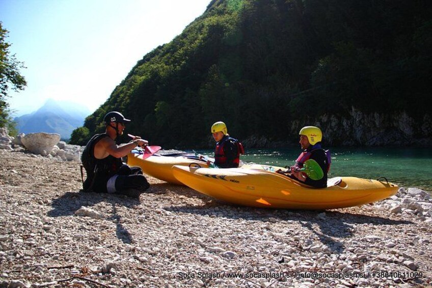 Three people in yellow kayaks on a rocky shore with a mountainous backdrop. 5