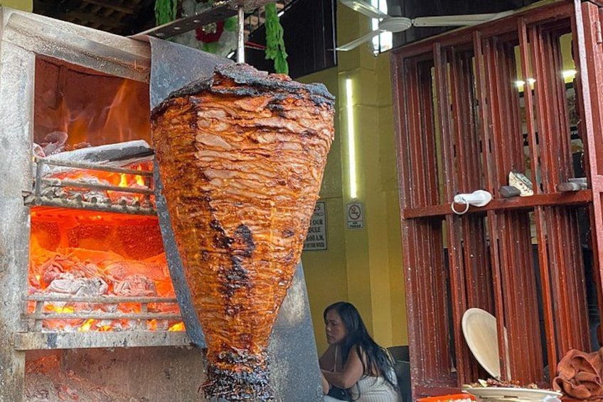 Un asador vertical con carne asándose sobre fuego. 3