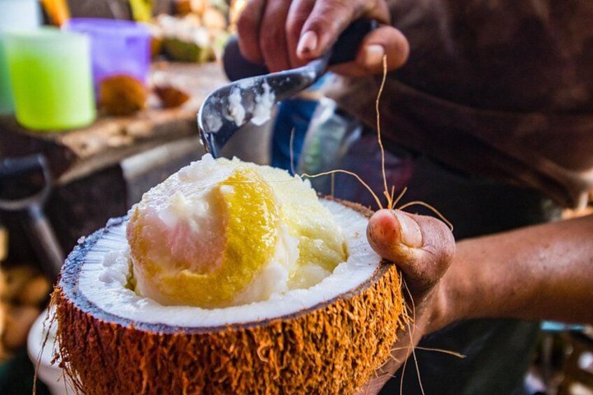 Una persona sosteniendo un coco con una bola de helado encima. 4