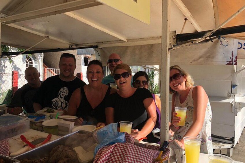 Un grupo de personas sentadas a una mesa con comida y bebidas, bajo una carpa. 3