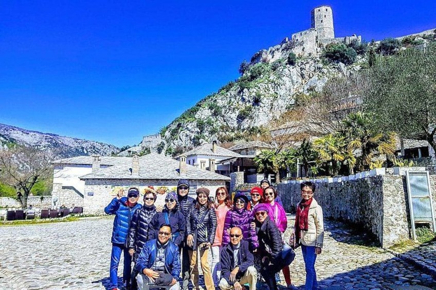 Un gruppo di persone che posa di fronte a un edificio in pietra con una torre su una collina. 1