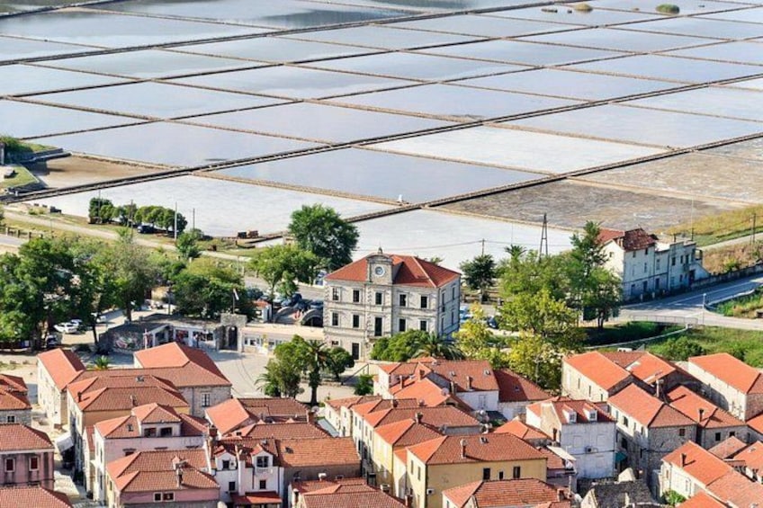 Una cittadina costiera con edifici dai tetti rossi, una vasta distesa d'acqua e pannelli solari. 5