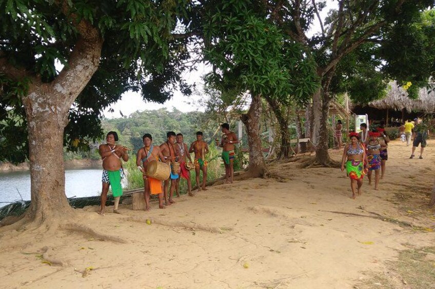 People standing by a river, some with bags, under trees. 5