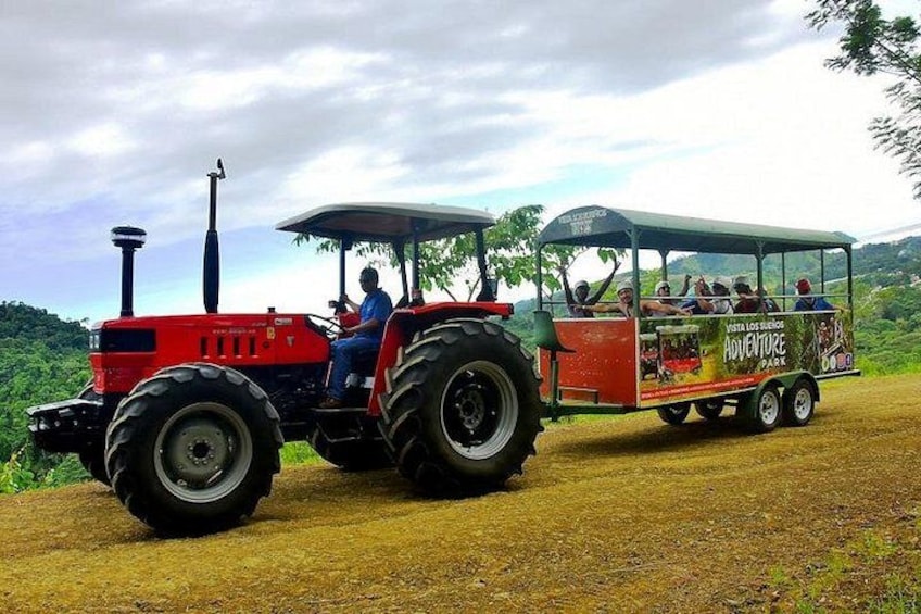 A red tractor pulling a tourist bus with 'Costa los Cuervos Adventure Park' written on it. 2