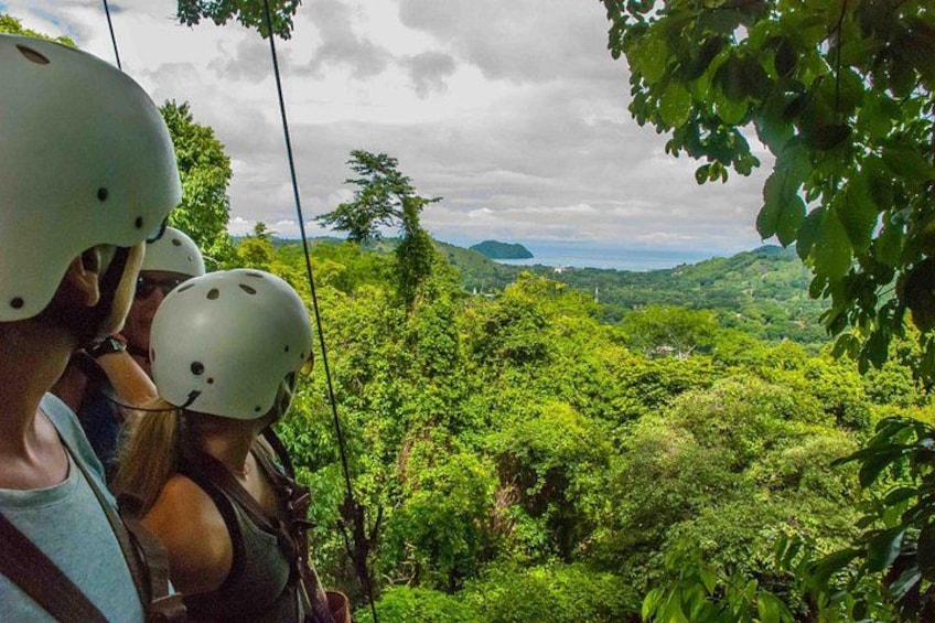 Mensen op een zipline met een weelderig groen landschap op de achtergrond. 4