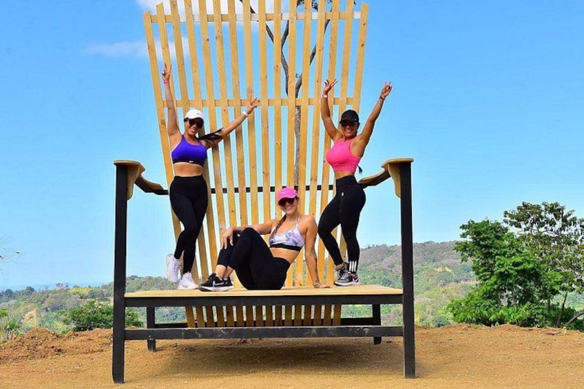 Three people on a wooden chair with a scenic landscape in the background. 2