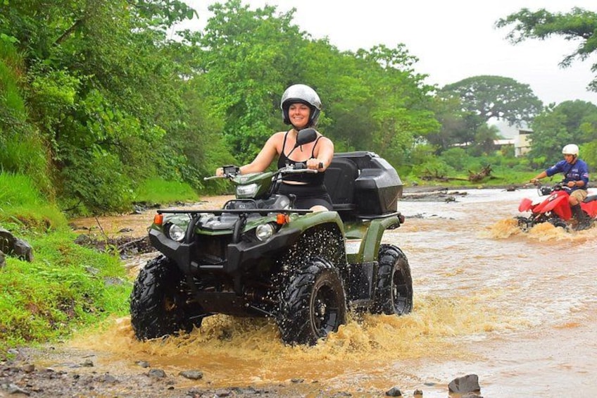 A person riding an ATV through a flooded area with another ATV in the background. 2