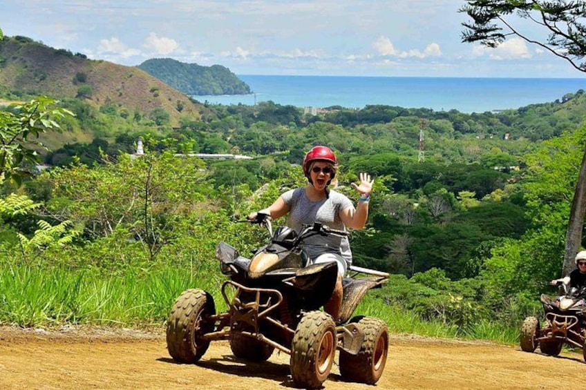 En person på en quad bike vinker, med et smukt landskab i baggrunden. 5