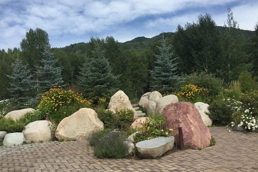 A landscaped garden with large rocks, flowering plants, and coniferous trees. 2