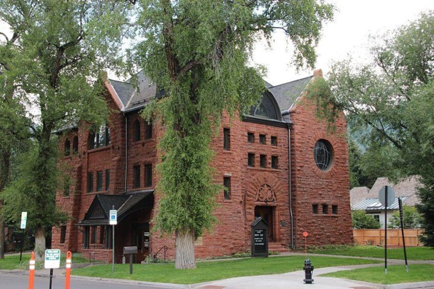A brick building with a clock tower, surrounded by trees. 3