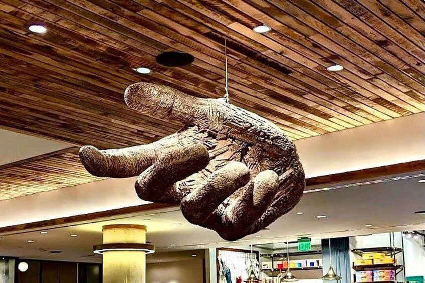 A large sculpture of a hand hanging from the ceiling in a modern building. 2