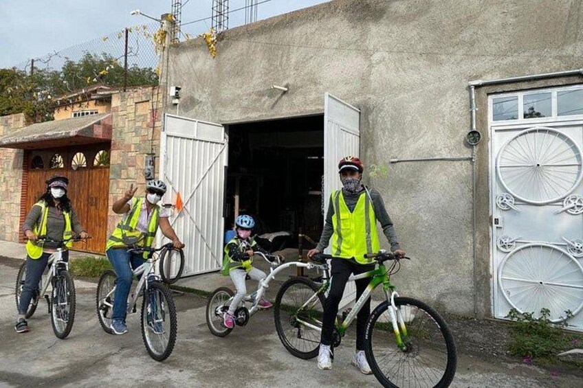 Vier fietsers met veiligheidsvesten, een gebouw met een garagedeur en een betonnen muur. 2