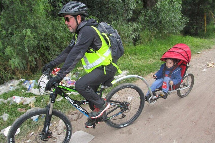 A person riding a bicycle with a child in a red trailer. 2