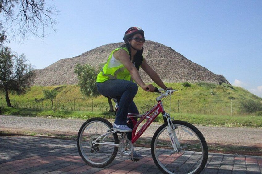 A person riding a red bicycle on a paved path with a hilly landscape in the background. 5