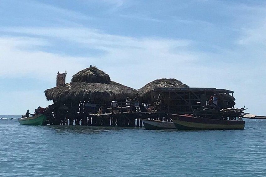 Una estructura flotante con techos de paja y personas en botes a su alrededor. 4