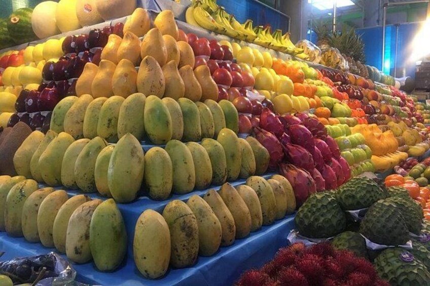 Un marché aux fruits où l’on trouve une variété de fruits, comme des mangues, des fruits du dragon et des bananes. 2