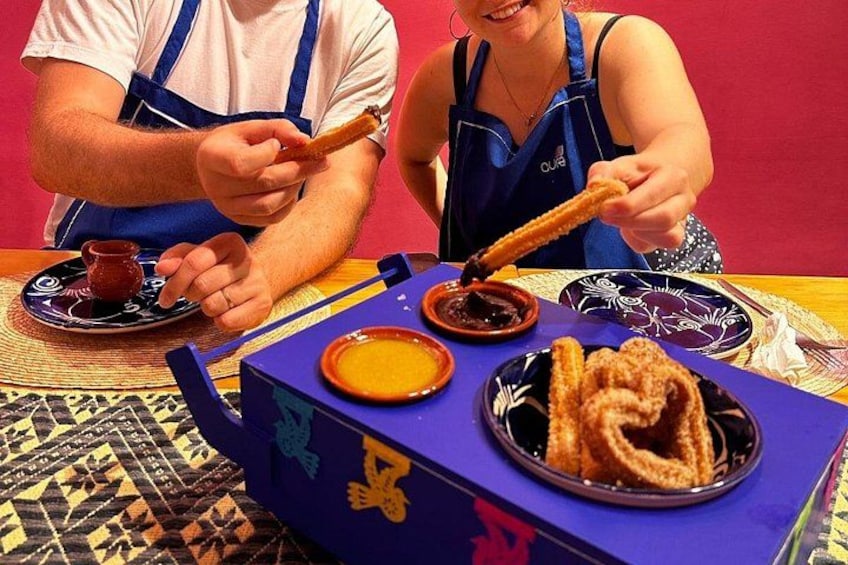 Zwei Personen genießen Churros mit Schokoladensauce, eine kleine Schüssel Sauce und einen Teller Churros. 4