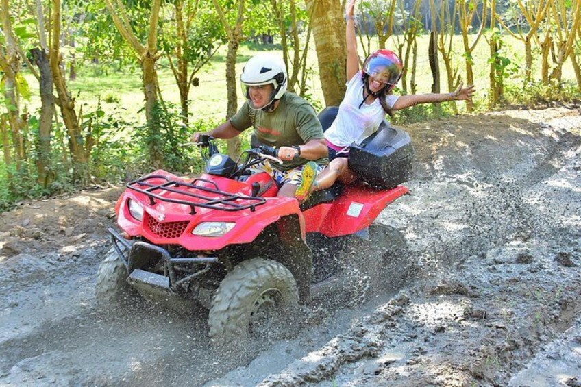 A person riding a red ATV on a dirt path surrounded by trees. 4