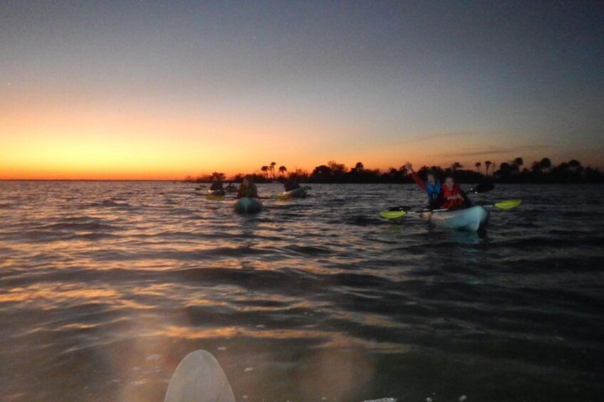Un atardecer sobre aguas tranquilas, con kayaks y gente. 5