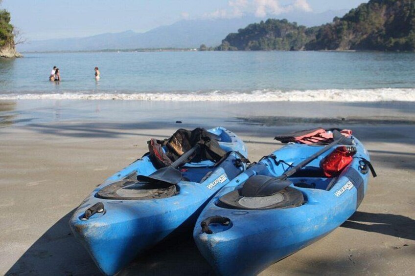 Deux kayaks bleus sur une plage, avec une eau calme et des montagnes à l’horizon. 4