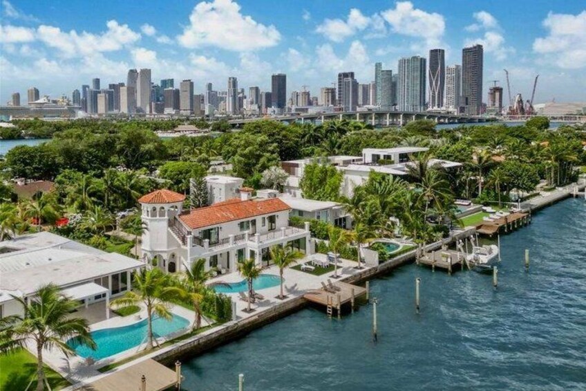 A waterfront property with a swimming pool, dock, and a city skyline in the background. 2