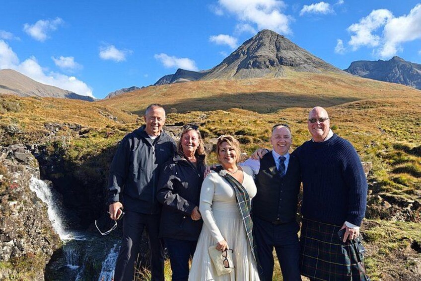 A group of people standing in a mountainous landscape with a waterfall. 2