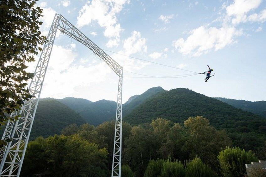 A person bungee jumping with a metal frame structure and a mountainous landscape in the background. 4