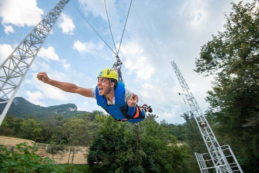 A person bungee jumping with a harness and helmet, with a mountainous landscape and power lines in the background. 3