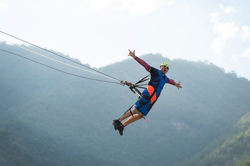 A person bungee jumping with a harness and safety lines, against a backdrop of misty mountains. 2