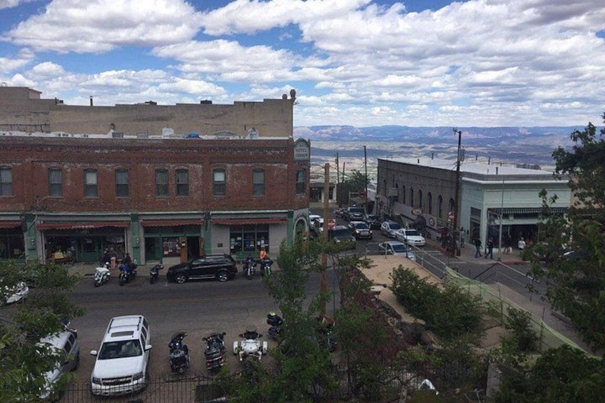 Un pueblo con edificios, coches aparcados y un paisaje montañoso al fondo. 4
