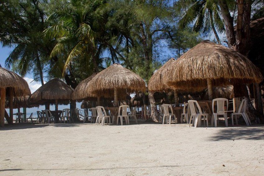 A beach with thatched umbrellas and plastic chairs. 4