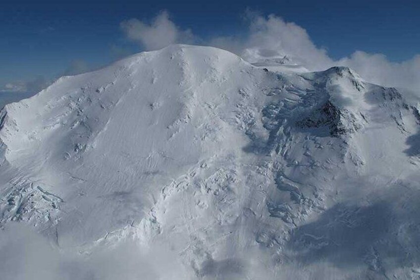 Een met sneeuw bedekte bergtop met ruig terrein en een heldere lucht. 2