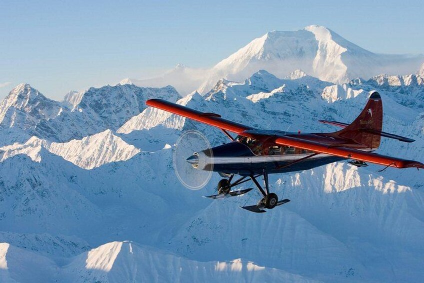 Un avion rouge et blanc survolant des montagnes enneigées. 4