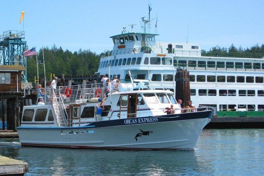 A boat named ORAS EXPRESS docked at a pier with a large ferry in the background. 2