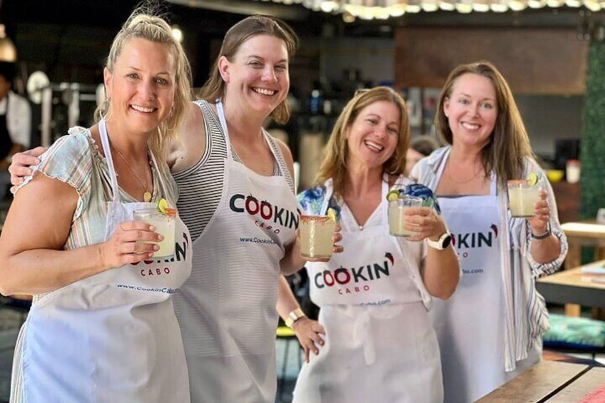 Fire personer i hvide forklæder med 'COOKIN' trykt på, holder drikkevarer. 2