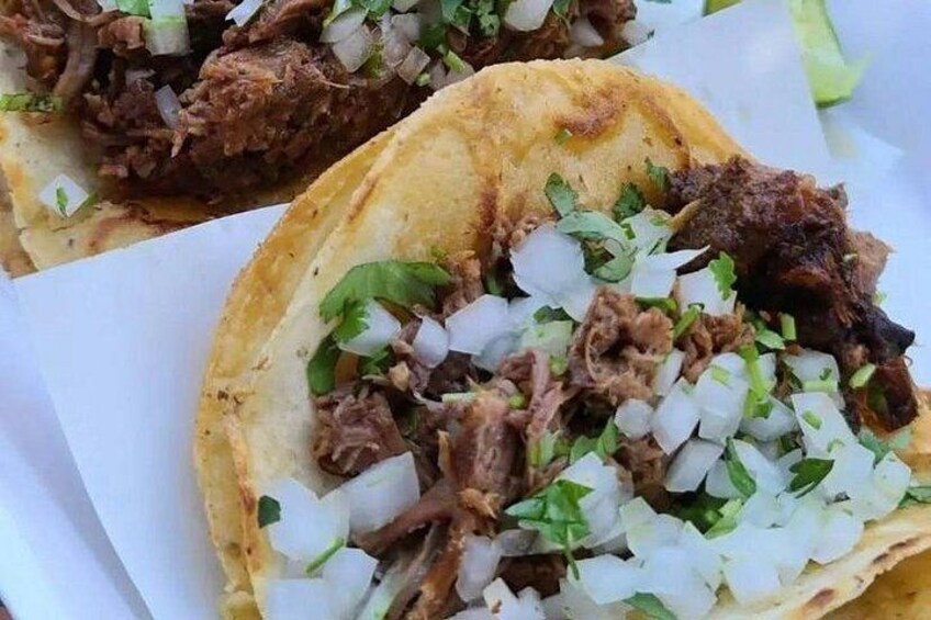 Een close-up van een taco met geraspeld vlees, blokjes ui en fijngehakte koriander. 1