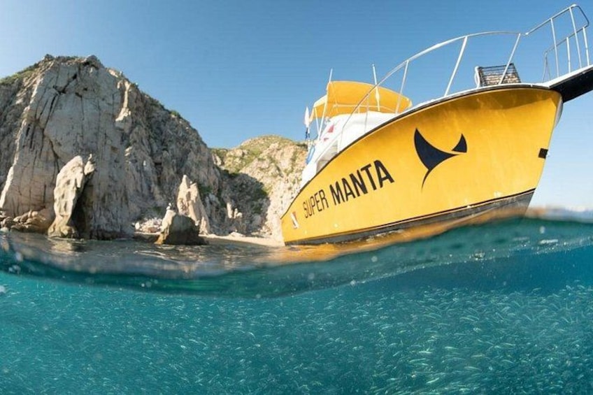 A yellow boat named SUPER MANTA near rocky cliffs in clear blue waters. 3