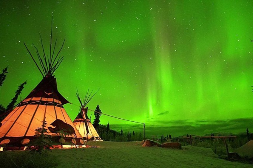 A night scene with three tipi-style tents under a green aurora borealis. 4