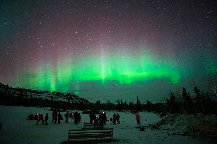 A night scene with the Northern Lights over a snowy landscape with people and a dock. 2