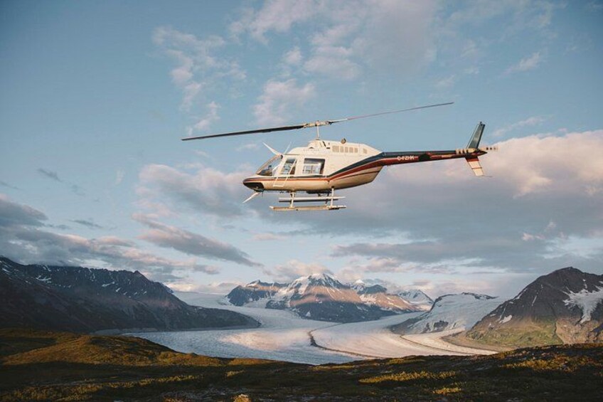 Un helicóptero sobrevolando un paisaje montañoso con un lago y picos nevados. 4